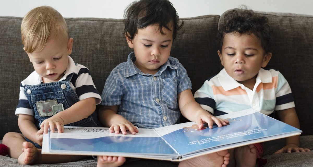 three toddler's reading a book